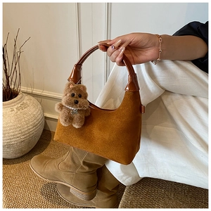 Detail of vintage brown suede tote bag with plush bear charm and sleek leather strap