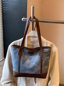 Retro denim and brown leather tote bag with large capacity hanging on a metal rack
