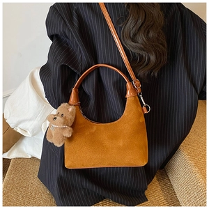 Detail of caramel suede hobo bag with teddy bear charm and adjustable shoulder strap