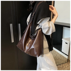 Side view of dark brown gloss leather tote bag worn by a model for daily commute use