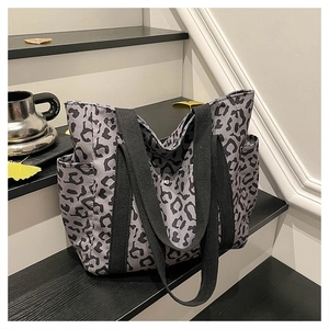 Detail of leopard print tote bag featuring black woven handles and side storage pockets