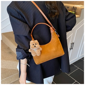Detail of vintage caramel suede tote bag with chain strap and teddy bear charm