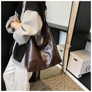 Detail of a large coffee brown tote bag showing its soft texture and slouchy design on a shoulder