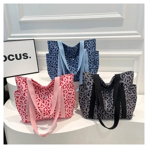Detail of leopard print canvas tote bags in pink, blue, and grey with wide strap handles