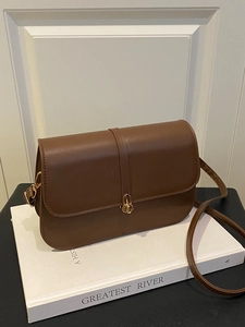 Retro brown baguette bag with golden buckle on a white book prop for a stylish look