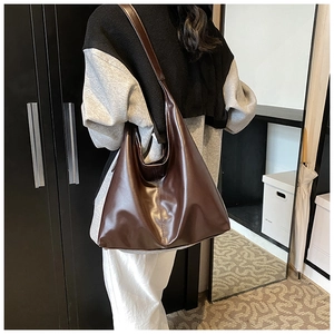 Detail showing deep brown faux leather tote bag being worn as a shoulder bag