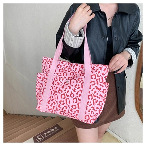 Pink leopard print tote bag with red spots and side pockets shown in a street style shot