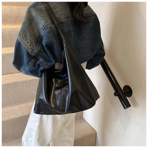 Fashionable black matte leather hobo bag with wide strap on model in outdoor setting