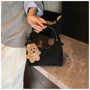 Detail of black matte hobo bag with plush bear charm and glossy shoulder strap