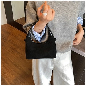 Detail of a vintage black frosted hobo bag with a sleek handle held by a model