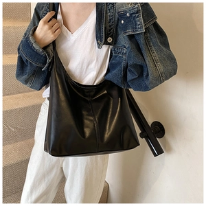 Close-up of a black leather tote bag with vertical stitching on outdoor stairs