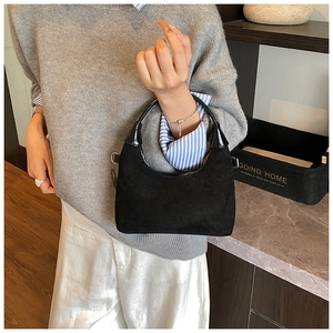 Detailed shot of black matte suede hobo bag with glossy leather handle and silver rings