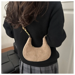 Close-up of suede crescent bag featuring double stitching and adjustable gold hardware