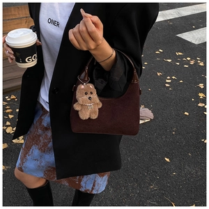 Detail of dark brown suede Hobo shoulder bag with a cute plush bear charm on a street