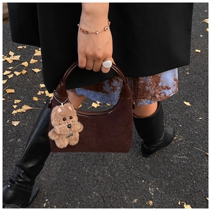 Detail of dark brown suede tote bag with leather handle and plush puppy charm