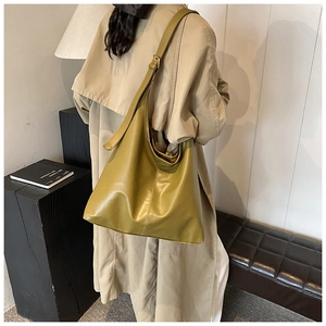 Olive green large tote bag with adjustable shoulder strap shown on a model in a modern room