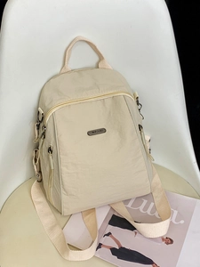 Minimalistischer beiger Nylon-Reiserucksack für Damen auf einem Stuhl im lässigen Stil