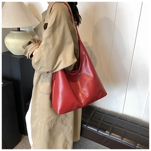 Fashionable large red leather hobo bag worn with a beige trench coat for a chic daily look
