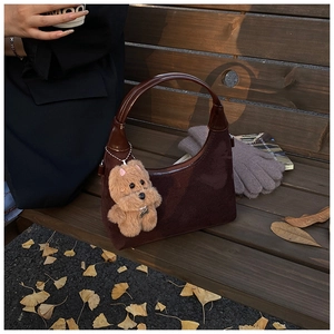 Detail view of a vintage dark brown suede tote bag with a cute puppy plush keychain charm