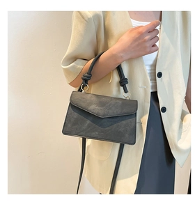 Dark gray matte leather crossbody bag with unique knot handle and golden metal ring detail