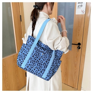 Detail of blue leopard print tote bag with side pocket shown on a shoulder strap