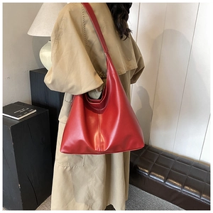 Close-up of a burgundy large tote bag with glossy leather texture on model shoulder