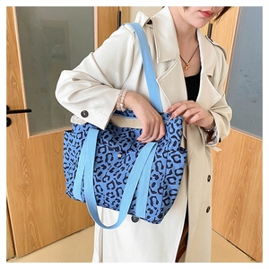 Detail view of the side pocket and blue fabric strap on this leopard print canvas tote bag