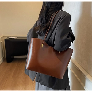 Detail of a large dark brown leather tote bag showing capacity and side view on a model