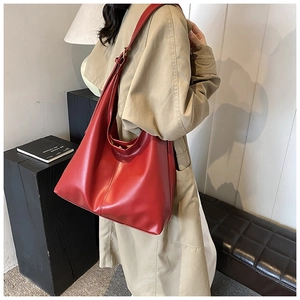 Red large capacity faux leather tote bag worn by model over a khaki trench coat