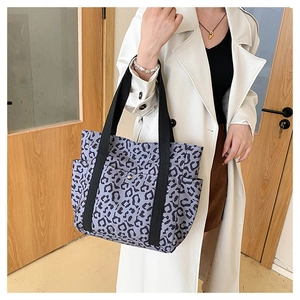 Detailed side view of leopard print tote bag with black straps and side pockets