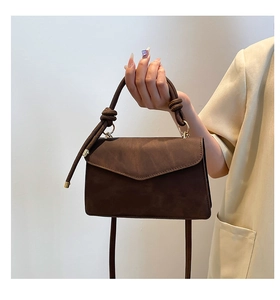 Detailed view of dark brown frosted leather bag with knot handle and golden accents