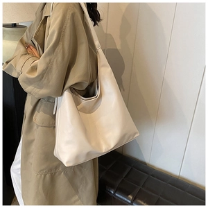 Minimalist cream tote bag with vertical stitching and wide strap shown on a model