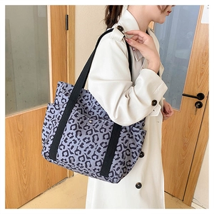 Leopard print tote bag with black shoulder straps shown on model in home setting