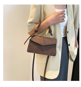 Detail of dark brown leather handbag with knotted handle and vintage textured finish