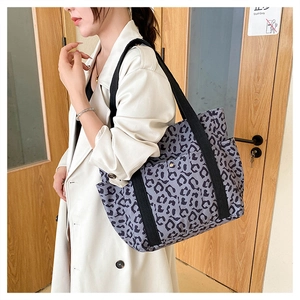 Detail of leopard print tote bag with black wide strap and metal buckle on front pocket