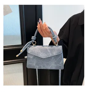 Detail of gradient grey-blue crossbody bag with marble texture and knot handle design