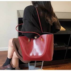 Detail view of burgundy glossy tote bag with slim shoulder strap and golden hardware
