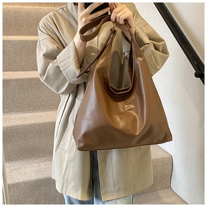 Detail of a brown soft leather tote bag showing vertical stitching and large capacity