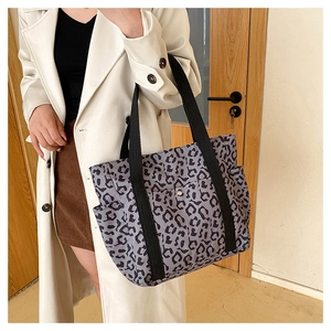 Detailed side view of a large leopard print tote bag with black handles and side pocket