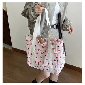 Détail de la texture d'un cabas en velours côtelé rose avec motif fraises et anses blanches