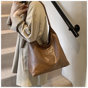Detailed side view of large brown matte leather hobo bag with vertical stitching