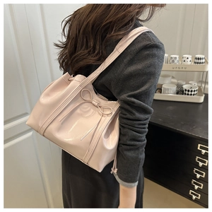 Side view of a large pink glossy PU leather tote bag worn by a model in a modern room