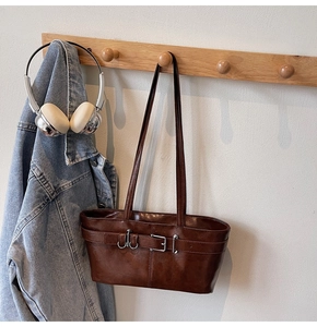 Vue détaillée du sac baguette marron foncé avec finition vintage et boucles en métal décoratives