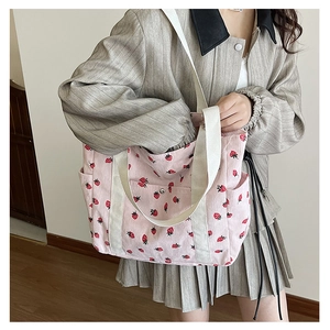 Détail d'un sac cabas en velours côtelé rose avec broderies fraises et poches latérales