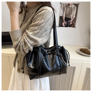 Close-up of black glossy PU leather tote bag with elegant bow and drawstring details