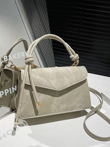 Stylish light grey crossbody bag with denim texture and knotted handle on mirror display