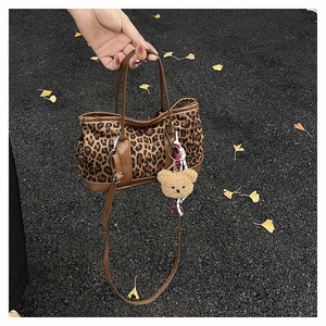 Detail of vintage leopard print handbag with brown leather handles and teddy bear charm