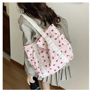 Détail d'un sac cabas en velours côtelé rose à motif fraises et bandoulière crème