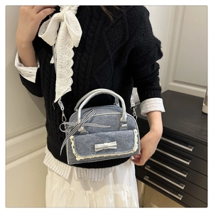 Detail of grey-blue denim bag with lace trim, silver bow, and detachable shoulder strap