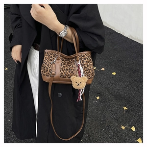 Detail of leopard print bucket bag with brown suede trim and cute teddy bear charm